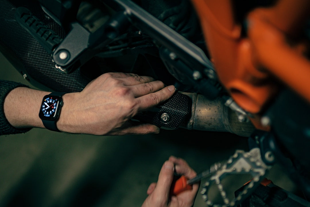 A close up of a person's hands in leather gloves checking the chain of a motorcycle
